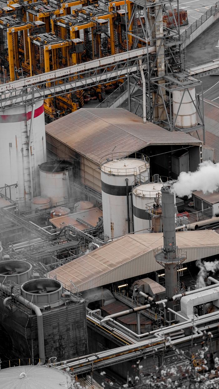 Bird's-eye view of intricate machinery and pipework at an industrial factory, showcasing production activity.